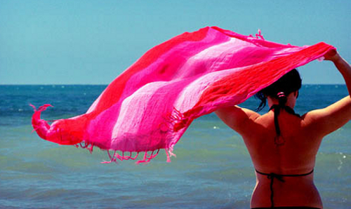 Нудистка в красном парео на пляже 